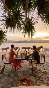 吉利阿萨汉吉利阿萨汉生态小屋及餐厅假日公园的一群人坐在海滩上的桌子上