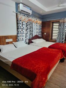 坎努尔Sunshine Service Villa的一间卧室配有两张带红色床单的床和电视。