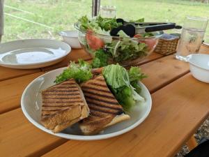 美作Glamchette Okayama -Glamping & Auto Camp- - Vacation STAY 44593v的木桌上盘子里的三明治和沙拉