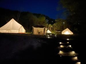 美作Glamchette Okayama -Glamping & Auto Camp- - Vacation STAY 44575v的两个帐篷在晚上在黑暗中点燃