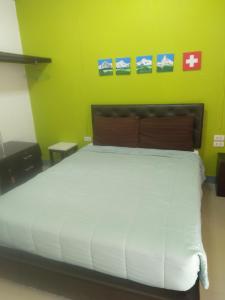 清莱清迈萨布迪帕里斯公寓式酒店的一间卧室配有一张白色的床和绿色的墙壁