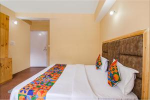 马拉里FabHotel Nirvana Deluxe的卧室配有一张带彩色枕头的大型白色床。
