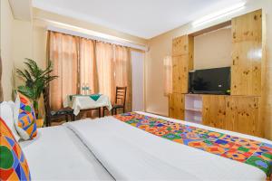 马拉里FabHotel Nirvana Deluxe的一间卧室配有一张床、一台电视和一张桌子