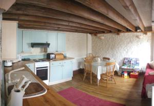 巴里The Old Barn的厨房配有蓝色橱柜、桌子和桌子。