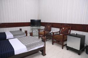 卡拉尔哥特Hotel Serina Inn的一间卧室配有两张床、一台电视和椅子