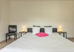 L'Antre d'Eux - Suite avec sauna et jacuzzi的一张带粉红色枕头和两把椅子的白色床