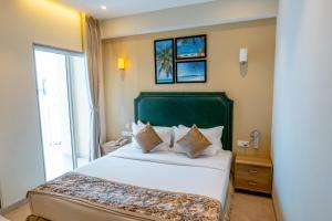 马累Hotel Flora Inn Male Maldives的一间卧室配有一张大床和绿色床头板