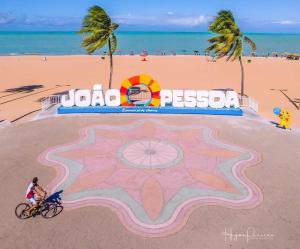若昂佩索阿Chocolate com pimenta Edifício - Praia do Bessa的骑自行车在海滩上的人