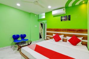 加尔各答OYO Tara Maa Guest House的绿色卧室,配有床和2把蓝色椅子