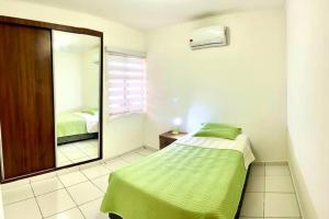 圣克鲁斯HERMOSA Y COMODA CASA " En condominio Privado "的一间卧室配有绿色的床和镜子