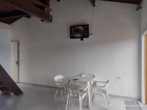 伊利亚贝拉Chalé do Saulo的白色的用餐室配有白色的椅子和墙上的电视