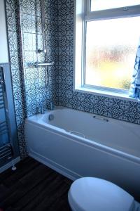 格兰瑟姆Fully renovated spacious home, Sleeps 5,的带浴缸、卫生间和窗户的浴室