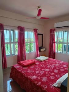 古鲁瓦尤尔2 BHK Furnished Flat - 200 m to Guruvayur Temple - For FAMILIES ONLY的一间卧室配有一张带红色床单和窗户的床。