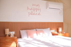 PasarbaruAshamaya Belitung (Dome Glamping Site)的卧室配有一张床,墙上有快乐的地方标志