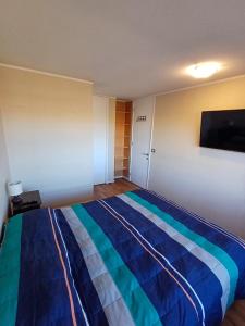 卡拉马Departamento Central en Calama的一间卧室配有一张带蓝色条纹毯子的床