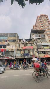 达卡Hotel New Royal Palace Dhanmondi的一条城市街道,有一座有人和自行车的建筑