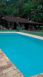 圣塞巴斯蒂安Hostel Recanto Caiçara的房子前面的蓝色游泳池