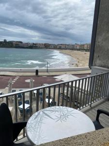 桑亨霍Alojamientos Plaza Portugal的阳台配有桌子,享有海滩美景