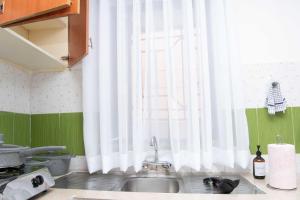 基苏木Tina's 1 BR Apartment with Fast Wi-Fi, Parking and Netflix - Kisumu的厨房配有水槽和带白色窗帘的窗户。