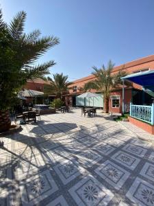 Dawmat al Jandalفندق ادوماتو ADOMATo HOTEl的一座建筑前方的庭院,庭院里种植了桌子和棕榈树