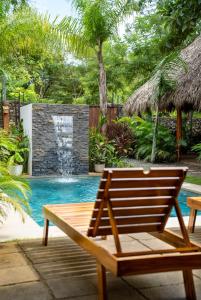 阿维拉纳海滩Villa Ave del Paraíso的一个带瀑布的游泳池旁的木凳