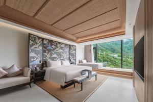 腾冲腾冲暻阁半山温泉酒店的一间卧室配有一张床、一张沙发和一个窗口