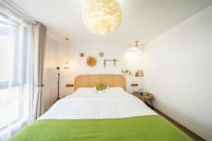 青浦小喜屋（西井街店）的白色卧室配有一张带绿毯的大床