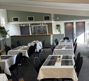 MurgonMurgon Motor Inn的用餐室配有白色桌子和黑色椅子