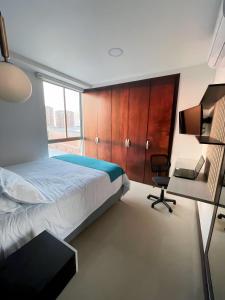 巴兰基亚Atlantis Suites Bquilla -Apartamento Moderno-2-BD的一间卧室配有一张床、一张桌子和一把椅子