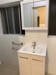 悉尼Gardens of Eden Sydney North的浴室设有白色水槽和镜子