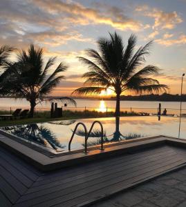 波隆纳鲁沃Hotel Lake Park的一座拥有两棵棕榈树和日落的游泳池