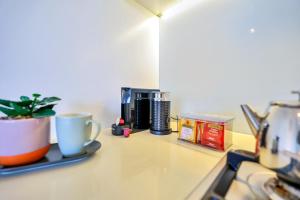 达尔文Cute & Cosy Darwin Waterfront Apartment with Queen Bed的台面、咖啡壶和咖啡杯