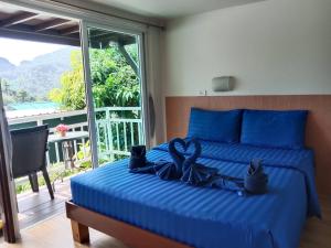 皮皮岛Blue View House Phi Phi的一间卧室配有一张带蓝色床单的床和一扇窗户。