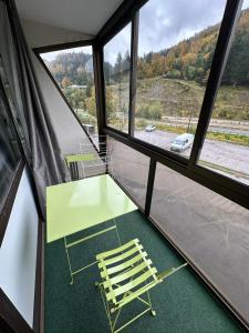 拉布雷斯Studio situé au pied des pistes de LaBresse的窗户间配有一张绿桌和一把椅子