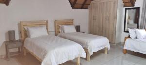 SandtonLAPA ROOF的一间卧室配有两张带白色床单和镜子的床
