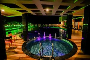 曼达莫尼Prasant Beach Resort的游泳池在晚上设有喷泉