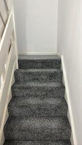 伦敦7 Venus Road (Room 7)的一间铺有黑色地毯的房间内的楼梯