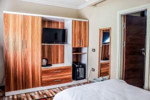 开罗LOVELY PYRAMIDS motel的一间卧室配有一张床、一台电视和木制橱柜。