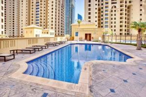 迪拜Modern 3BR Flat in the Heart of Dubai JBR的一座带长椅和建筑物的大型游泳池