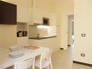 莱万托Residenza Cavour - Appartamento AGAVE的厨房配有白色橱柜和一张带白色椅子的桌子