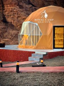 瓦迪拉姆ROYAl WADI RUM CAMP的岩石墙前的橙色帐篷