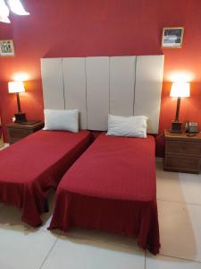 SalinaWhitestar Guesthouse的红色墙壁客房的两张床