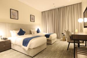 吉达فندق سافوي جدة Savoye Hotel的酒店客房配有两张床和一张书桌