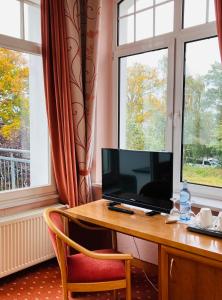 赛巴特班森哲迈尼尔酒店的窗户客房内的一张桌子、一台电视和一把椅子