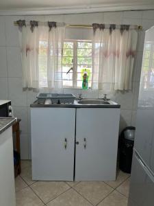 卢萨卡Furnished self catering cottage的白色的厨房设有水槽和窗户