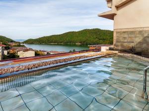 ObamaYukai Resort Unzen Toyokan的游泳池位于享有河景的建筑内
