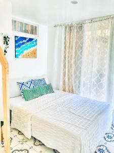 伊洛伊洛Balai Lawaan Charming Sanctuary的白色卧室配有蓝色和白色枕头的床