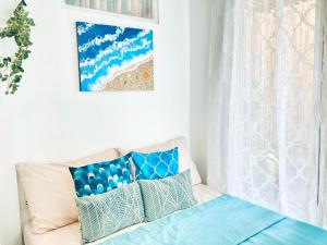 伊洛伊洛Balai Lawaan Charming Sanctuary的白色的客房配有带蓝色枕头的沙发