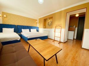 库塔伊西Hotel Orange Kutaisi的客房设有两张床、一张桌子和一张沙发。