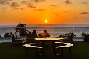 棕榈滩O Condominium Beachfront Residences, by Bocobay Aruba的坐在桌子旁看日落的夫妇